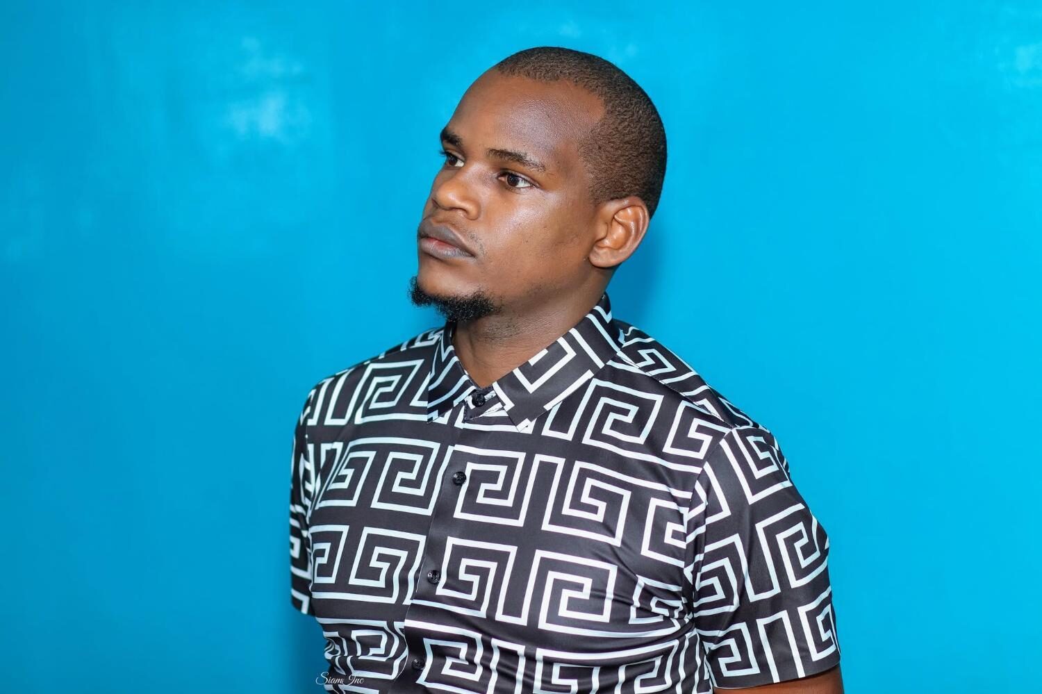 Man in patterned shirt against blue wall