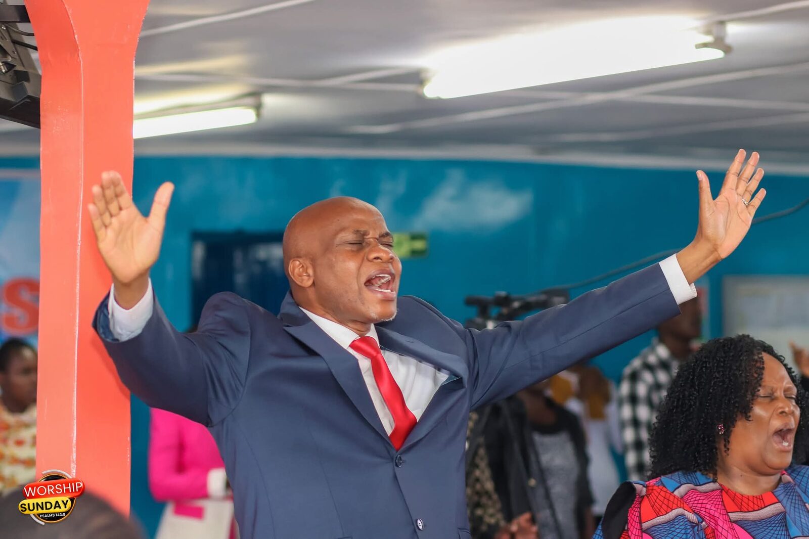 Bishop John Kaberere worshipping with arms raised