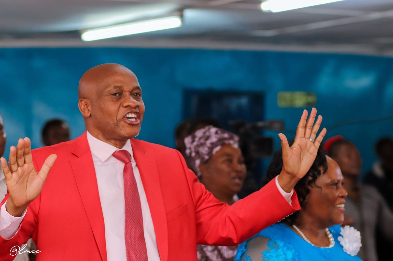 Bishop John Kaberere in red suit worshipping