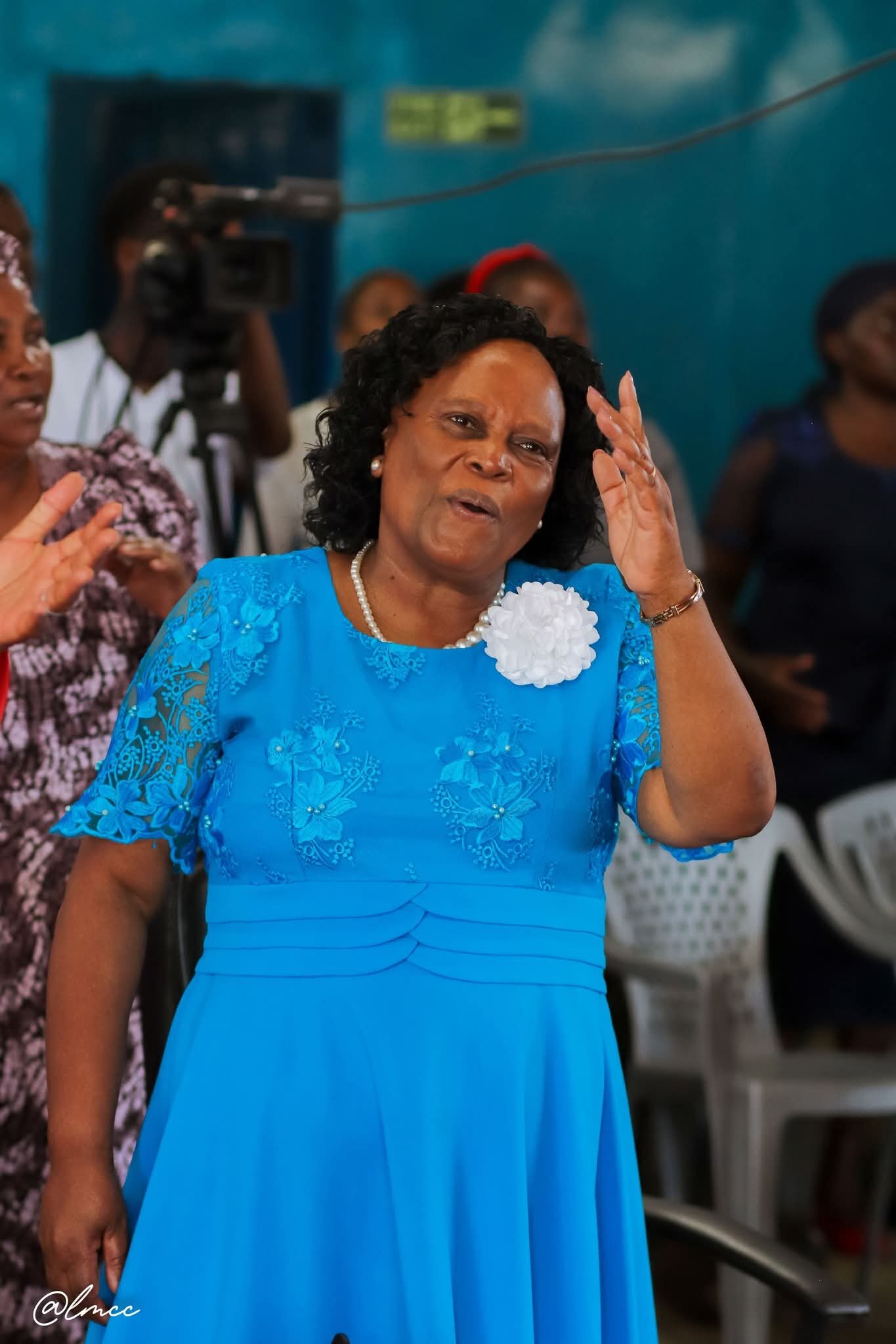 Woman in blue dress lifting hands in worship
